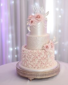 a three tiered wedding cake with pink flowers