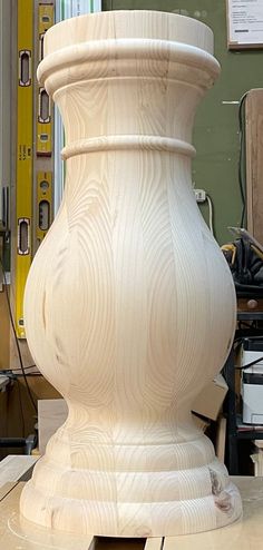 a large white vase sitting on top of a wooden table next to a pile of boxes