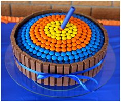 a cake made out of chocolate and colored candies with a blue ribbon around the edge