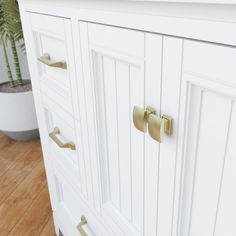 a white cabinet with brass handles and knobs