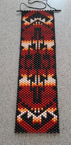 a long beaded piece on the ground with a black and red design hanging from it's side