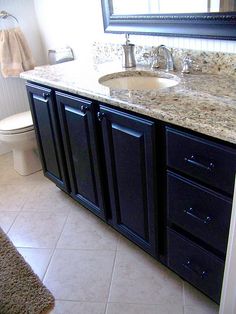 a white toilet sitting next to a bathroom sink under a mirror on top of a counter