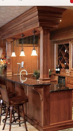 a kitchen with an island and bar stools next to it in front of a wine rack