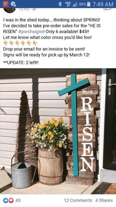 a wooden cross sitting on top of a porch next to flowers and a bucket full of flowers