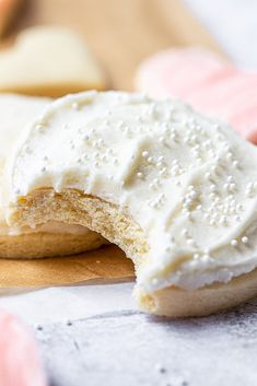 a cookie with white frosting on it sitting on a cutting board next to other cookies