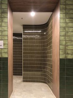 an empty bathroom with green tile walls and wood trimmings on the shower wall