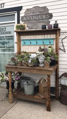 an outdoor potting bench with plants and pots on the top shelf in front of a building