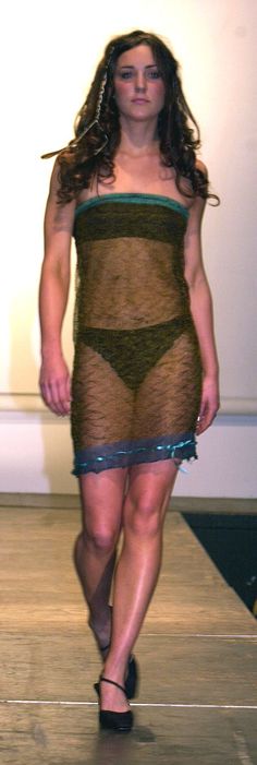 a woman is walking down the runway wearing a dress made out of fishnets