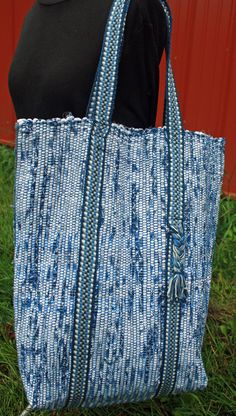 Handwoven blue and white tote bag.  This bag is woven with cotton warp threads and cotton fabric weft in the tradition of rag rugs.  The double straps are woven to match on an inkle loom and have a cute braided detail on one side.  The straps add support to the bottom of the bag and have a 9 inch drop.  The dimensions are 12 inches wide by 17 inches high by 5 inches deep giving plenty of room to stow all your gear for shopping, travel, the library or the beach.  Two interior pockets help keep things organized.  A 10 inch x 9 inch pocket secures with velcro and a 5 x 5 pocket is open for easy access to your phone or keys. I do my best to represent the colors accurately, but every monitor is different.  If in doubt about a color, please ask for a sample swatch. Eco-friendly Handwoven Blue Shoulder Bag, Eco-friendly Blue Handwoven Shoulder Bag, Blue Handwoven Shoulder Bag For Market, Blue Handwoven Tote Shoulder Bag, Decorated Tote Bags, Wool Tote, Azul Indigo, Inkle Loom, Rag Rugs