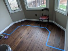 a chair sitting on top of a hard wood floor in a room with two windows