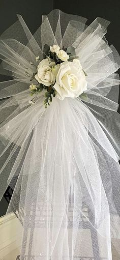 a white veil with flowers on the top and bottom is hanging from a door handle