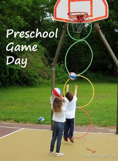 two children playing with hoop balls on a basketball court in front of a school game day sign