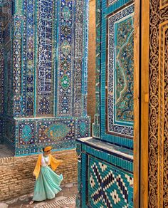 a woman in a blue and yellow dress is walking through an ornately decorated building