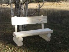 a wooden bench sitting in the grass next to a tree