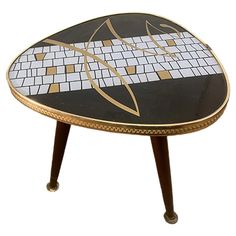 a black and white mosaic table with gold trimmings on the top, against a white background