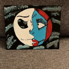 a painting of a woman's face painted in blue and red on a black background