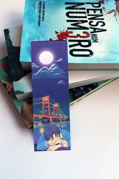 two bookmarks sitting next to each other on top of a white surface with an image of a bridge in the background