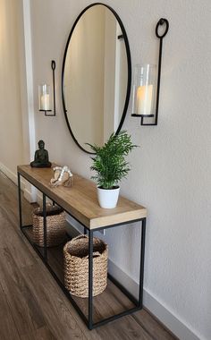 a wooden table topped with a potted plant next to a mirror and two wicker baskets