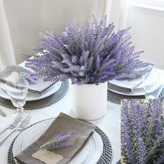 the table is set with purple flowers and place settings