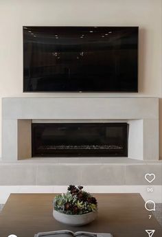 a living room with a large flat screen tv on the wall and a bowl of flowers in front of it