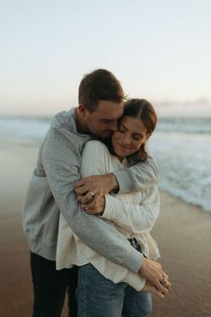 a man and woman hugging on the beach