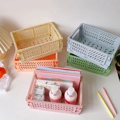 three plastic baskets filled with different items on a white counter top next to pencils and markers