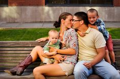 a family sitting on a park bench in front of a building