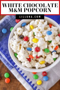 white chocolate and m & m popcorn in a bowl on a blue napkin with candy