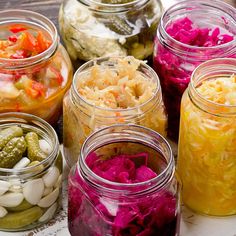 several jars filled with different types of vegetables and pickles on top of a table