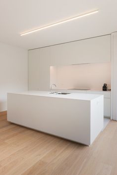 an empty kitchen with white cabinets and wood flooring