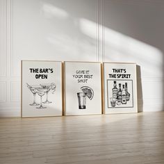 three framed posters on the wall in an empty room with wood flooring and white walls