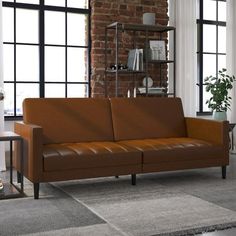 a brown leather couch sitting in front of a window