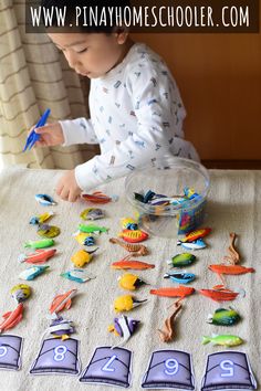 a toddler playing with numbers and magnets on a table in front of a window