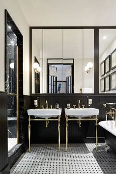 a black and white bathroom with two sinks, mirrors and a bathtub in it