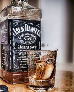 a bottle of jack daniels whiskey next to a glass with ice