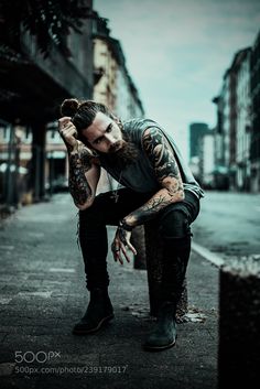 a man with tattoos is sitting on the curb