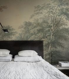 a bed with two pillows on top of it next to a lamp and wallpaper