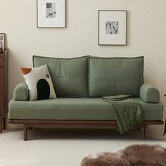 a living room with a green couch and two pictures hanging on the wall above it