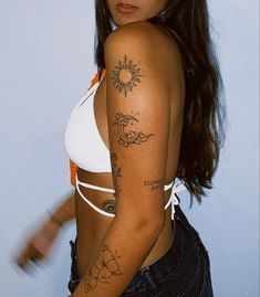 a woman with tattoos on her arm and chest standing in front of a white wall