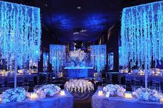 a room filled with lots of tables covered in white flowers and hanging chandeliers