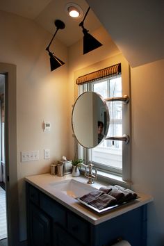 a bathroom with a sink, mirror and lights on the ceiling above it in front of a window