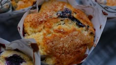 blueberry muffins wrapped in paper sitting on top of a table