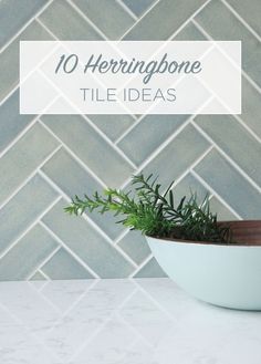 a white bowl filled with green plants on top of a counter next to a tile wall