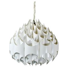 a white light hanging from a chain on top of a ceiling fixture with circular shapes