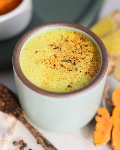 a cup filled with liquid sitting on top of a white table next to some spices