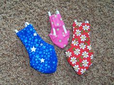 three small cloth toys are laying on the floor next to each other and one is pink, blue, and white