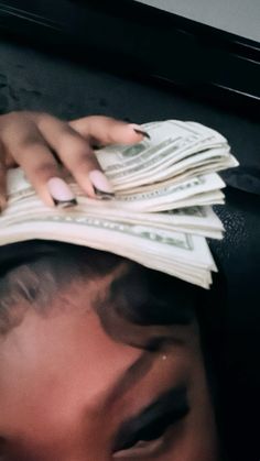 a woman with her hands on top of stacks of money in front of her face