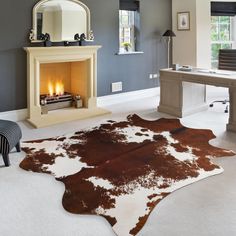 a living room with a fireplace and cow hide rug on the floor in front of it