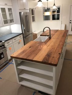 a kitchen with an island made out of wooden planks and metal appliances in the background