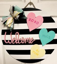 a welcome sign hanging on a door with paper hearts attached to the front and side